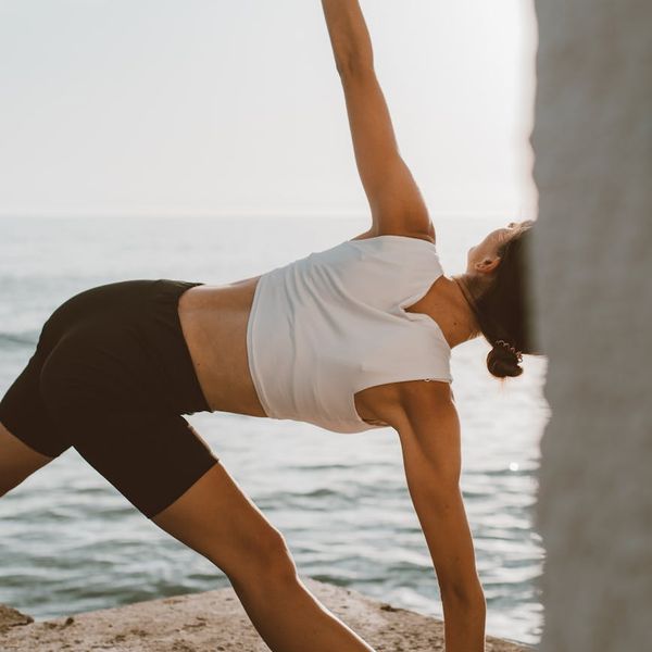 Person in a dynamic yoga pose outdoors during sunrise.